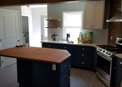 Modern kitchen with dark blue cabinets, wood countertop island, stainless steel appliances, and a brick backsplash—a perfect example of kitchen remodeling that turns any space into a culinary haven.