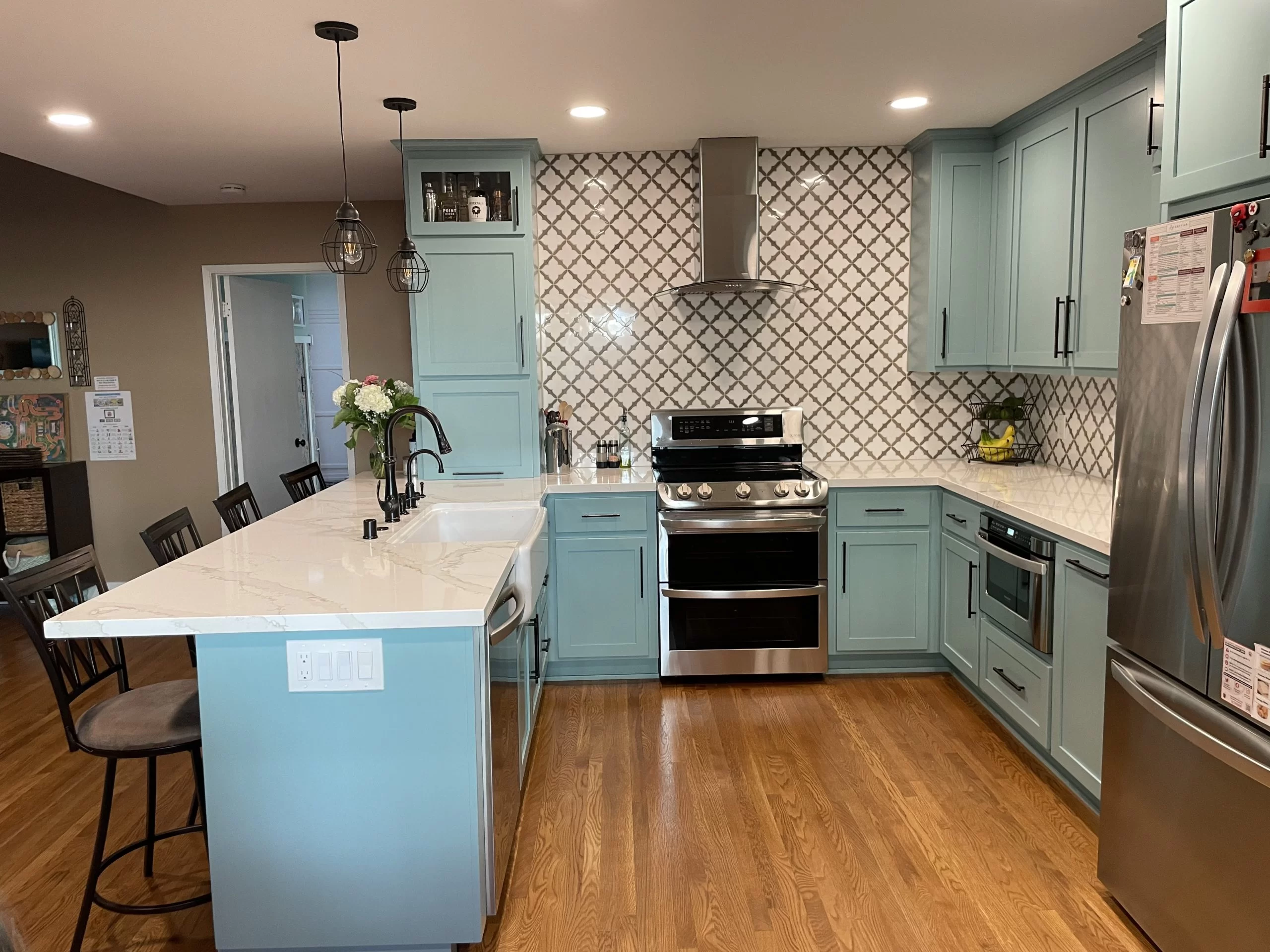 general contractor Los Angeles - Modern kitchen in Los Angeles with light blue cabinets, white countertop, stainless steel appliances, and wooden floor, expertly crafted by a top general contractor.