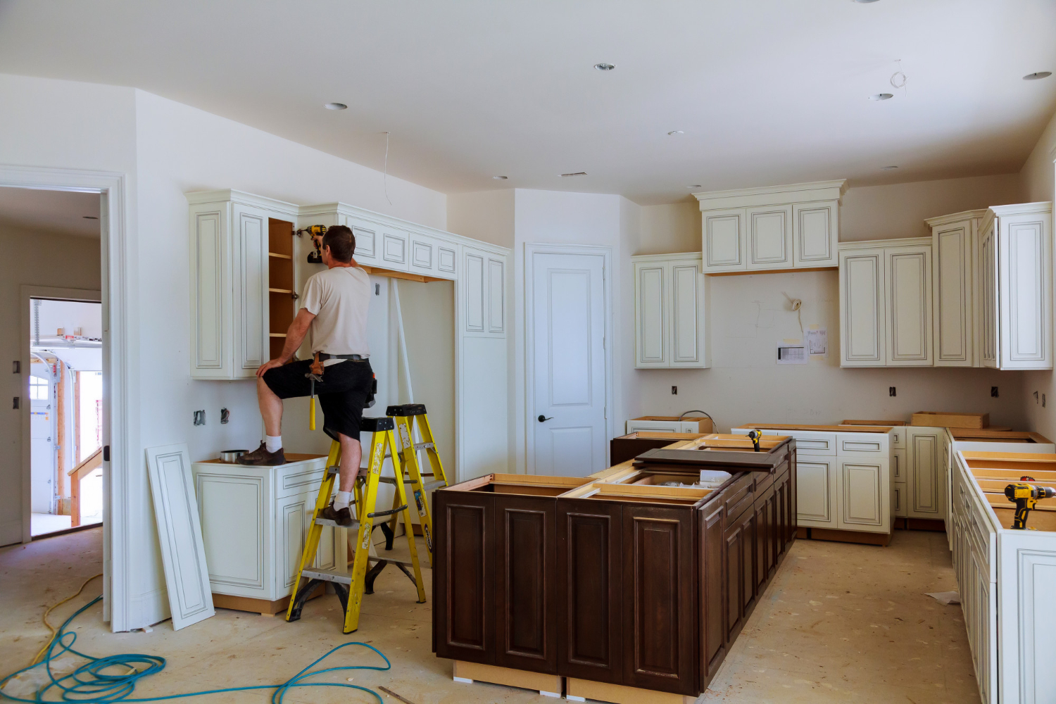 A person stands on a ladder installing cabinets in a kitchen under renovation. Home Remodeling Near Me